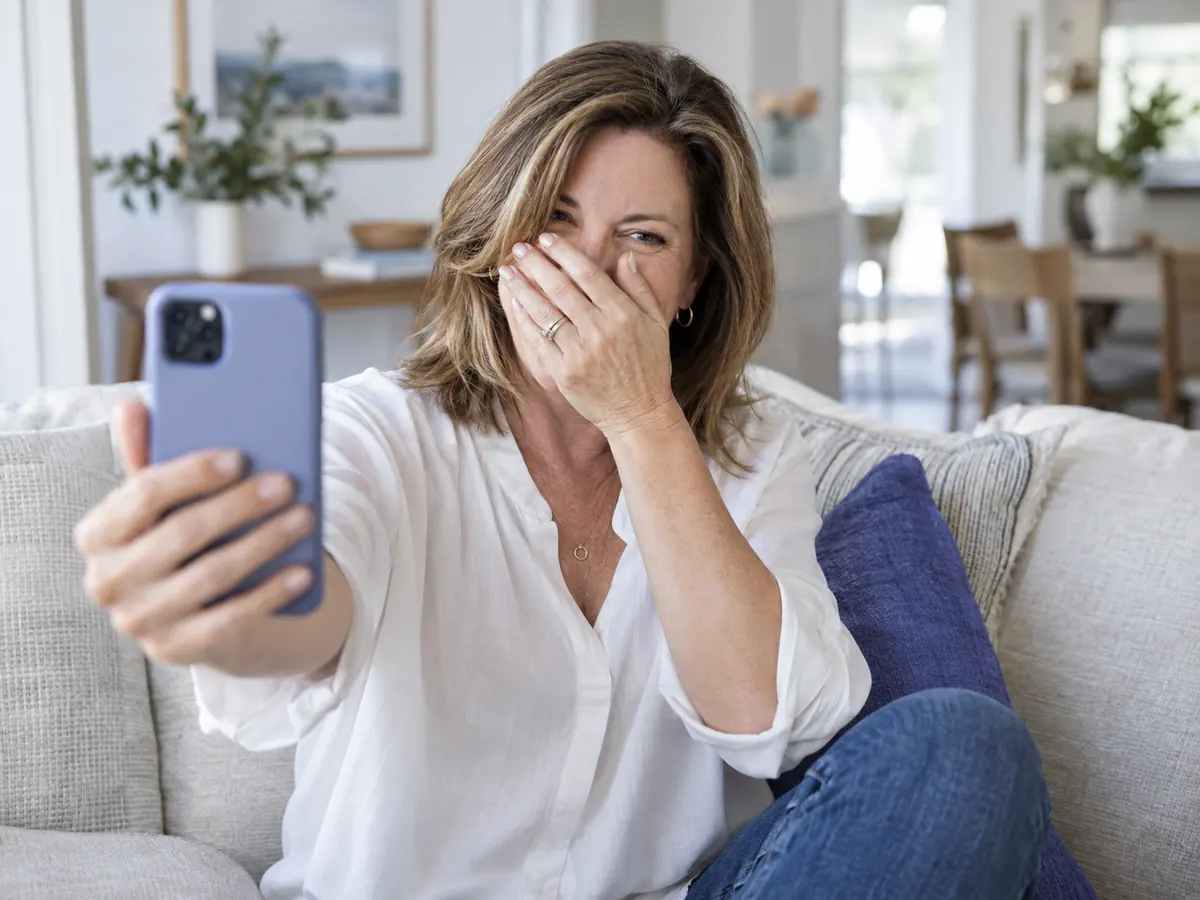 Agent laughing and half covering her face while holding up her phone